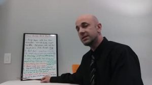 A man in a black shirt and tie sits at a table, pointing to a whiteboard with colorful handwritten text titled Free Rules That Work in the background. The setting appears to be an office or classroom, possibly where Rich Noto Realtor gives advice.